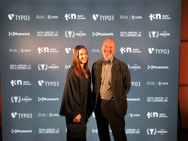 Sarah Haub und Götz Wegenast auf der TYPO3 Awards Gala vor einer großen Leinwand