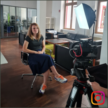 Foto einer sitzenden Frau beim Videodreh, Kamera auf sie gerichtet