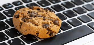 Cookie mit Schokostücken auf einer Mac-Tastatur