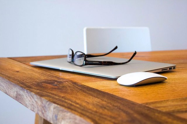 Brille auf einem geschlossenen Laptop auf einem Holztisch