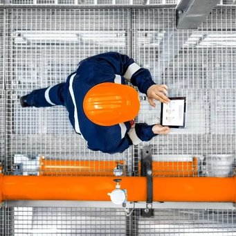 BARTEC - Mann läuft neben Pipeline der Ölförderplattform einer Raffinerie